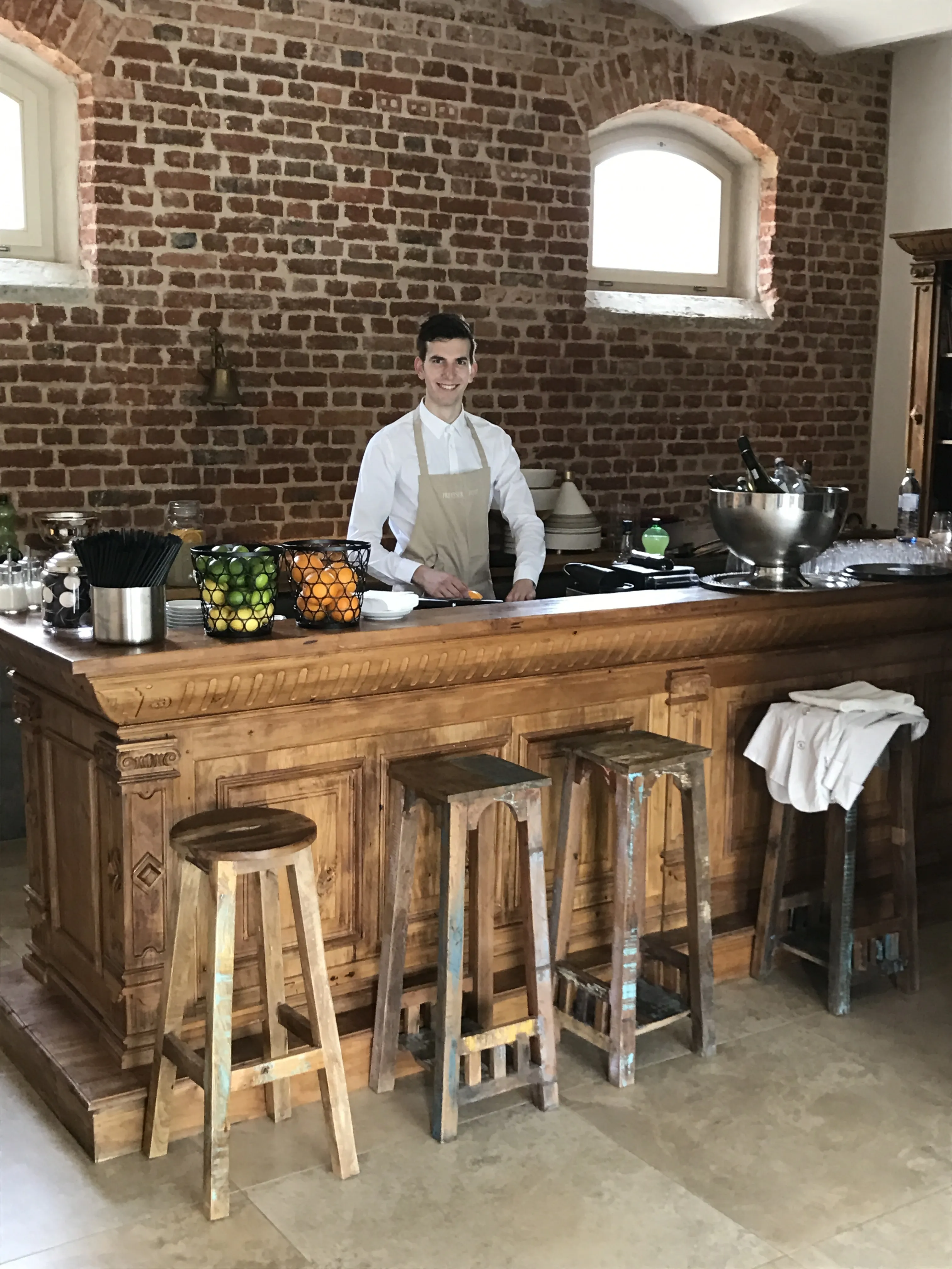 Barkeeper hinter einer Holzbar vor unverputzter Backsteinwand