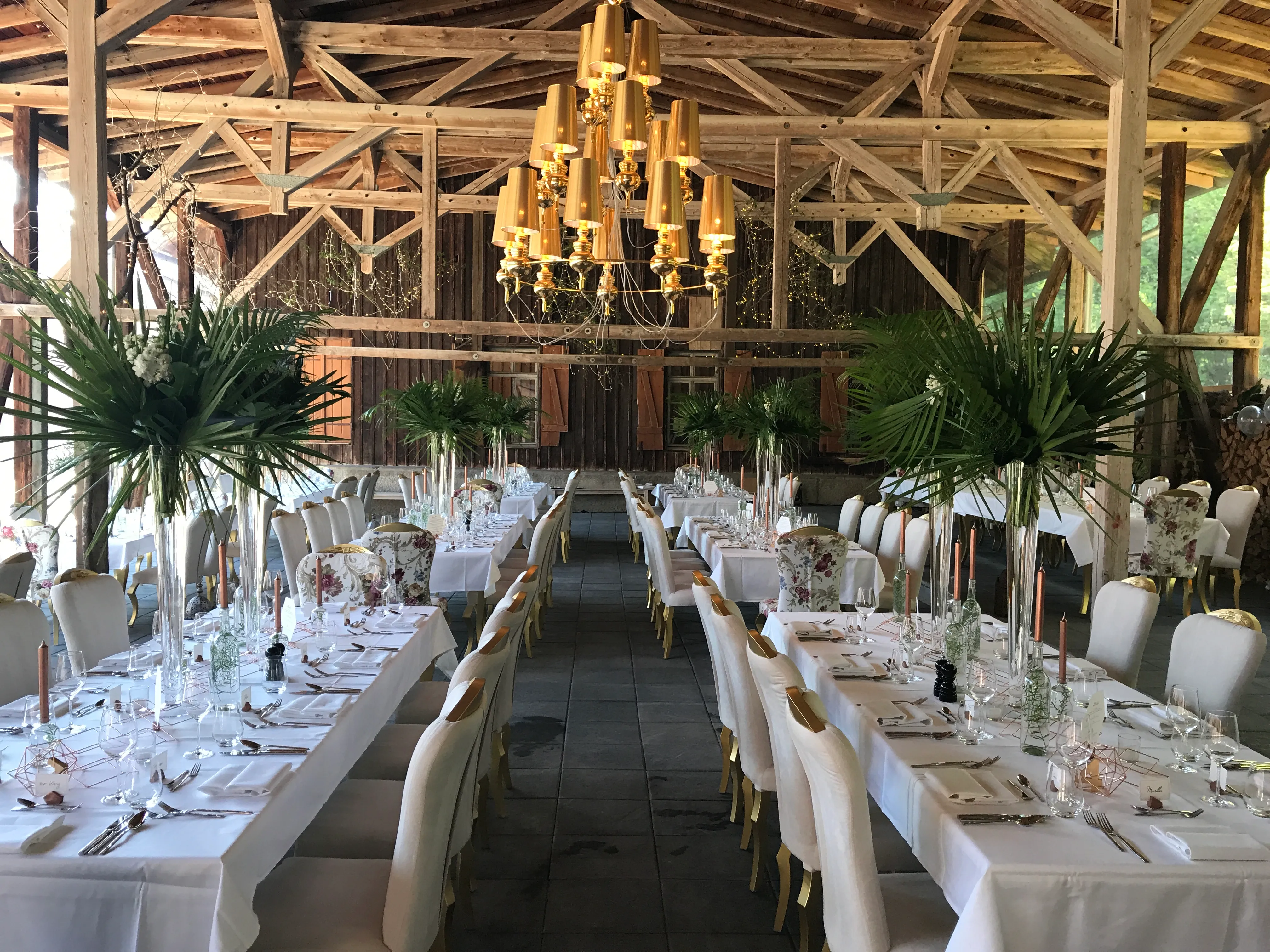 Festscheune mit langen Hochzeitstafeln, Lüstern und altem Gebälk