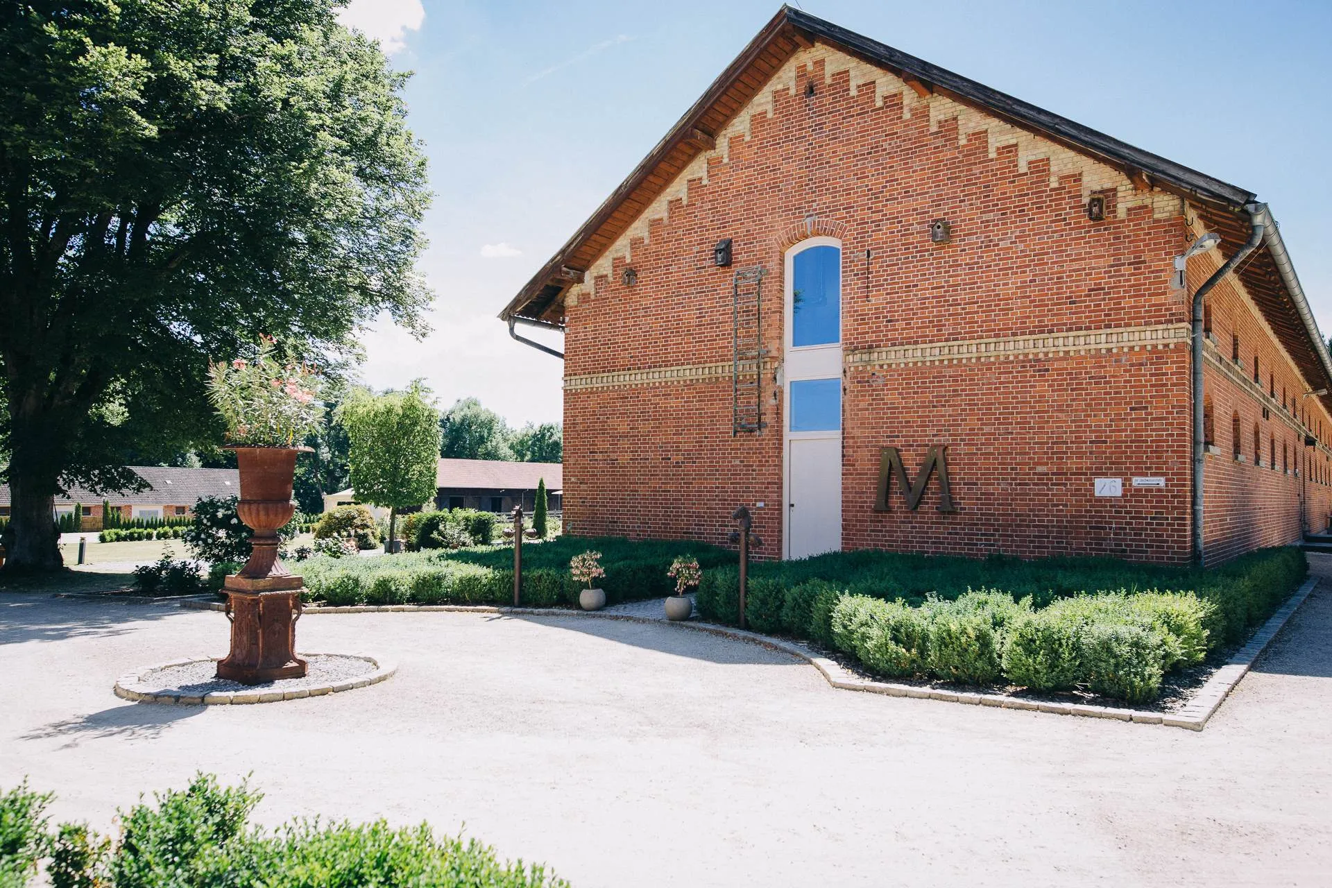 Giebel des historischen Stallgebäudes mit Monogramm und Brunnen