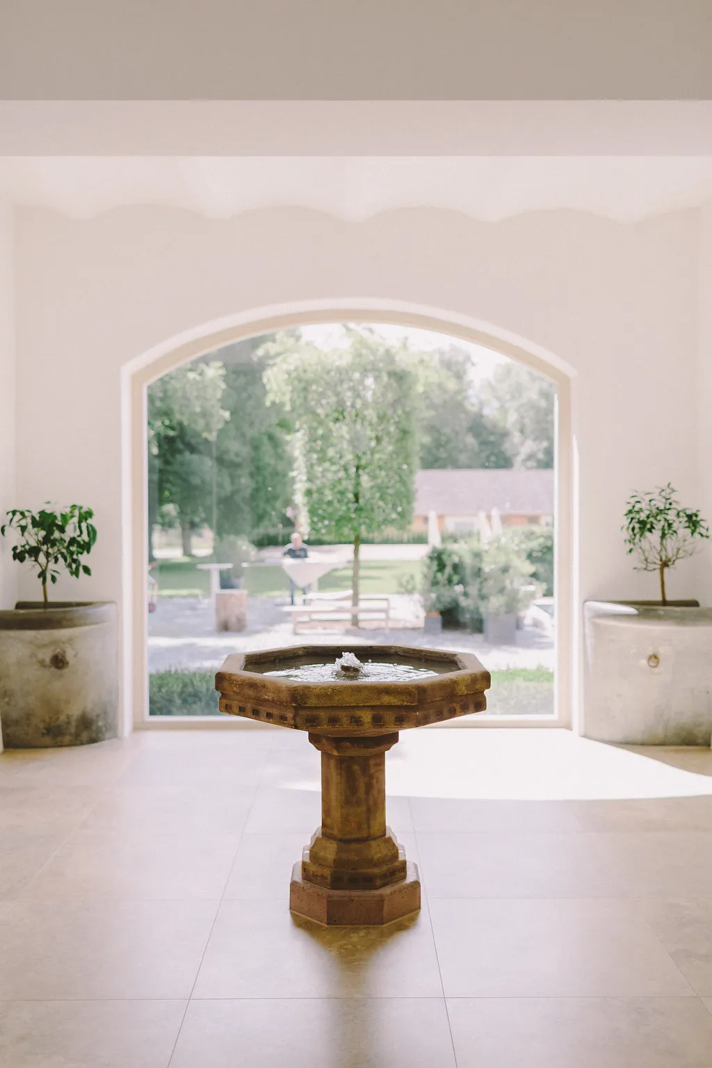 Bogenfenster der Villa mit Blick auf Brunnen und Park