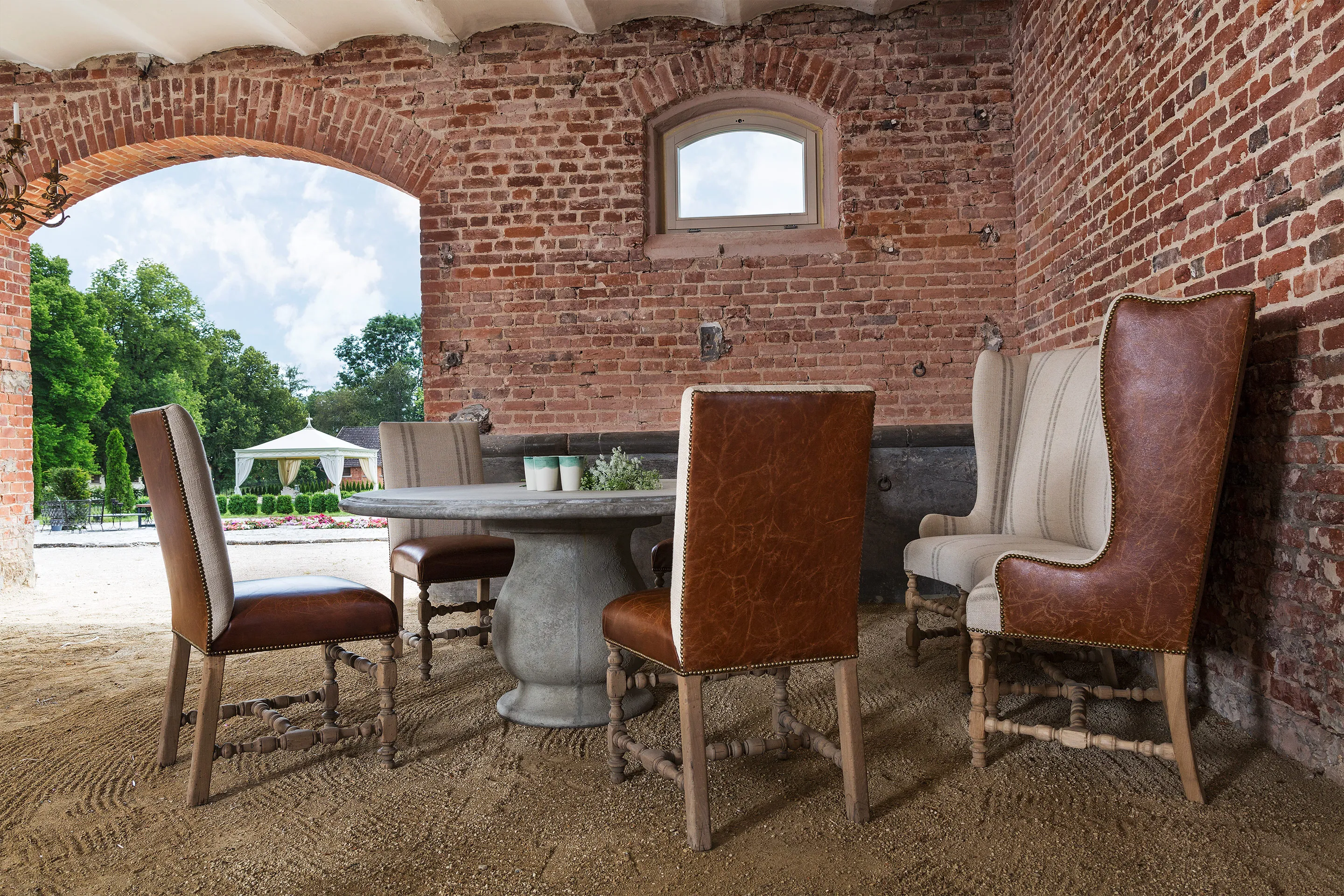 Loggia der Villa mit Ledersesseln unter Backsteinbögen, Blick zum Pool